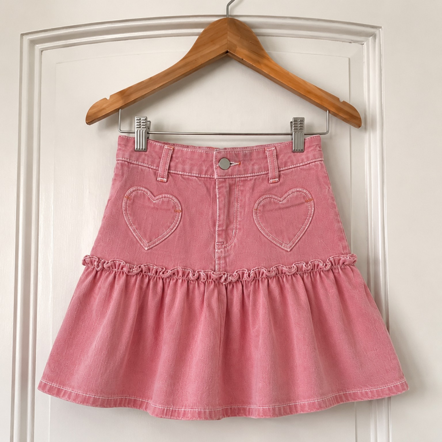 Customer photo of a rose-pink ruffle skirt hanging on a door